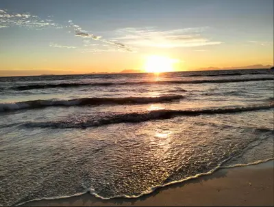 a sunset on a beach with the ocean at C es Cape in Pringle Bay