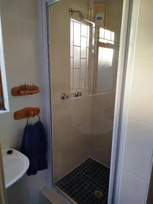 a shower with a glass door next to a sink at Mountain View Apartment in Cape Town
