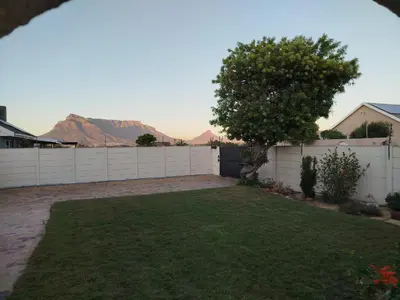 a yard with a white fence and a tree at Mountain View Apartment in Cape Town