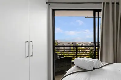 a bedroom with a bed and a view of a balcony at Two Bedroom Luxury Apartment, Century City - BackUp Power in Cape Town