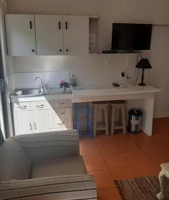 a kitchen with white cabinets and a sink and a counter at Voëlklip garden flat in Hermanus