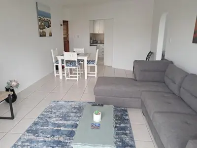 a living room with a couch and a table at 8 Marina Sands beach apartment in Cape Town