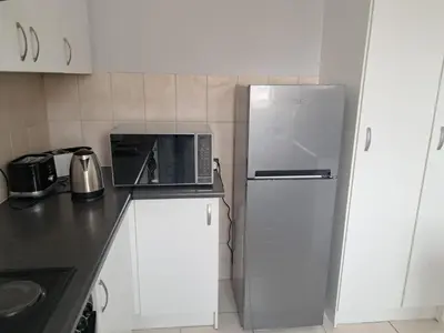 a kitchen with a refrigerator and a microwave at 8 Marina Sands beach apartment in Cape Town