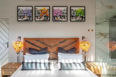 a bedroom with a bed with four pictures on the wall at The Glass Castle Retreat in Sir Lowry Pass