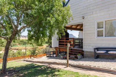 a house with a porch with a bench and a tree at Hephzibah Inn River Cabin in Hermon