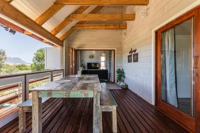 a wooden deck with a wooden table on a house at Hephzibah Inn River Cabin in Hermon