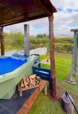 a pergola with a bed and a pile of wood at Hephzibah Inn River Cabin in Hermon