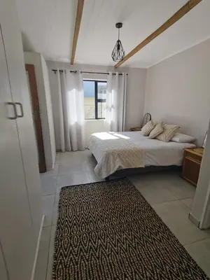 a bedroom with a bed and a rug on the floor at Shekinah at Sea in Kleinmond