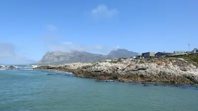 an island in the ocean with mountains in the background at Shekinah at Sea in Kleinmond
