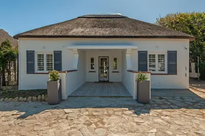 a white house with blue shutters and a door at Hermanus Garden Studios in Hermanus