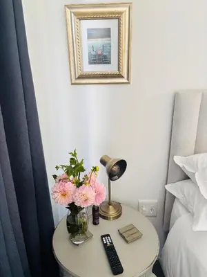 a table with a vase of flowers and a lamp at Hermanus Garden Studios in Hermanus