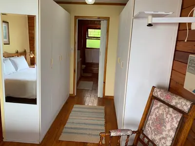 a hallway with a bed and a chair in a room at Bay View Cabin in Gordonʼs Bay