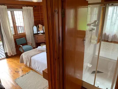 a bedroom with a bed and a glass shower at Bay View Cabin in Gordonʼs Bay