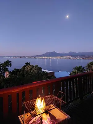 a fire pit on a balcony with a view of the water at Bay View Cabin in Gordonʼs Bay