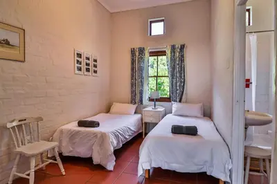 a bedroom with two beds and a sink and a window at Hilbre House in Bettyʼs Bay