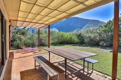 a picnic table and benches on a patio at Hilbre House in Bettyʼs Bay