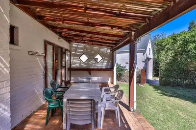 a patio with a table and chairs on a deck at Hilbre House in Bettyʼs Bay