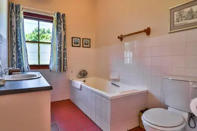 a bathroom with a tub and a toilet and a sink at Hilbre House in Bettyʼs Bay
