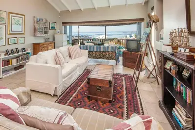 a living room with a white couch and a table at Whispering Waves in Hermanus