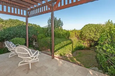 an outdoor patio with two chairs and a pergola at Whispering Waves in Hermanus