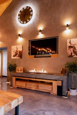 a living room with a fireplace and a clock on the wall at The Glass Castle in Sir Lowry Pass