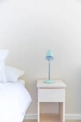 a nightstand with a lamp on it next to a bed at Lux Private Garden Studio - Sunset Beach in Cape Town