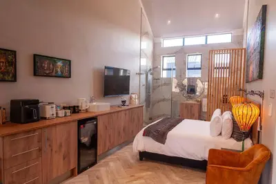 a bedroom with a bed and a bathroom with a shower at Golden Sunset Room in Sir Lowry Pass