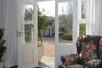 an open door with a chair in a living room at Jakaranda Cottage in Somerset West