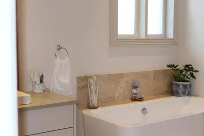 a bathroom with a white sink and a window at Jakaranda Cottage in Somerset West
