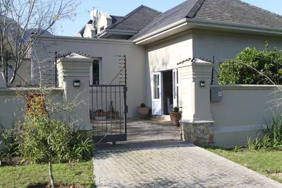 a white house with a gate and a driveway at Jakaranda Cottage in Somerset West