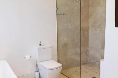 a bathroom with a toilet and a glass shower at Jakaranda Cottage in Somerset West