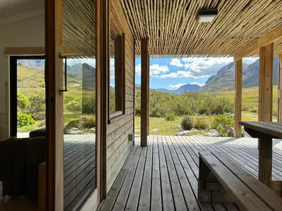 a wooden porch with a view of the mountains at The River Retreat Kogelberg in Kleinmond