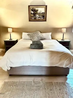 a bedroom with a large bed with two lamps at Simunye Cottage in Simondium