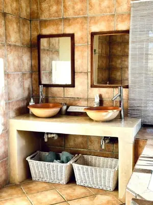 two sinks in a bathroom with two mirrors and baskets at Simunye Cottage in Simondium