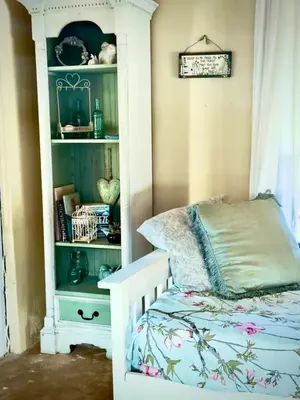 a bedroom with a bed and a book shelf at Simunye Cottage in Simondium