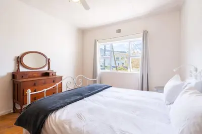 a white bedroom with a bed and a window at Coastal Elegant 4 Bedroom Home in Hermanus