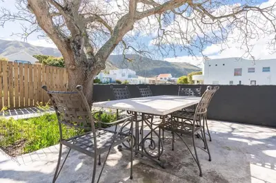 a table and chairs on a patio with a tree at Coastal Elegant 4 Bedroom Home in Hermanus