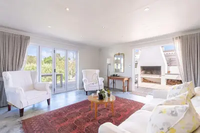a living room with a white couch and chairs and a table at Coastal Elegant 4 Bedroom Home in Hermanus