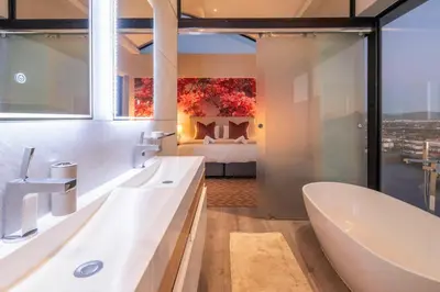 a bathroom with a bath tub and a bedroom at Penthouse with a view to die for! in Cape Town