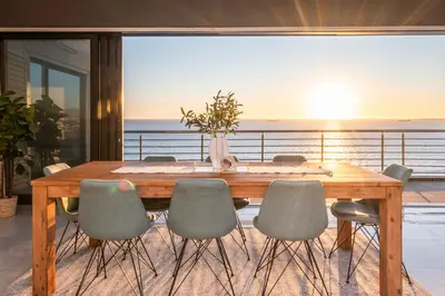 a dining room table and chairs with a view of the ocean at Penthouse with a view to die for! in Cape Town