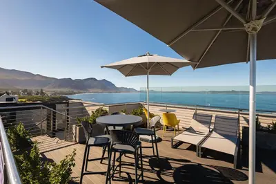 a patio with a table and chairs and an umbrella at Ocean Family Deluxe, Hermanus Waterfront Apartments in Hermanus