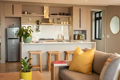 a living room with a couch and a kitchen at Ocean Family Deluxe, Hermanus Waterfront Apartments in Hermanus