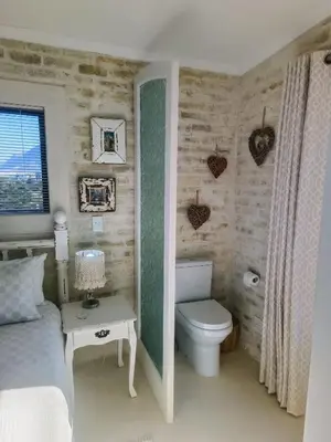 a small bedroom with a bed and a toilet at KLIPWERF Bettys Bay in Bettyʼs Bay