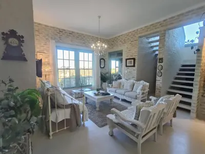 a living room with white furniture and a staircase at KLIPWERF Bettys Bay in Bettyʼs Bay