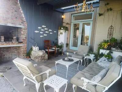 a patio with a couch and chairs and a table at KLIPWERF Bettys Bay in Bettyʼs Bay