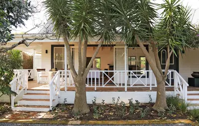 a house with palm trees on the front porch at Kumbuk House in Franschhoek
