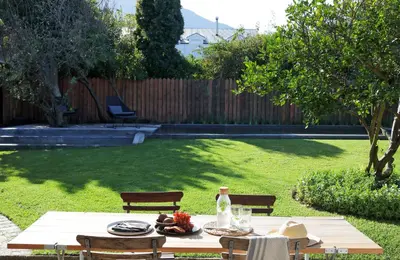 a table with a plate of food on it in a yard at Kumbuk House in Franschhoek