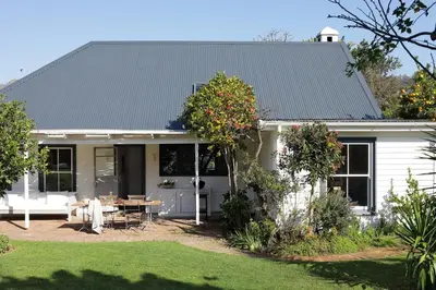 a white house with a table in a yard at Kumbuk House in Franschhoek