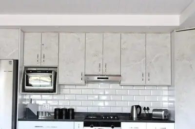 a kitchen with white cabinets and a microwave at Sea and Mountain View Apartment in Cape Town