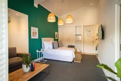 a bedroom with a white bed and a green wall at Studio 7 - Hermanus Waterfront Apartments in Hermanus